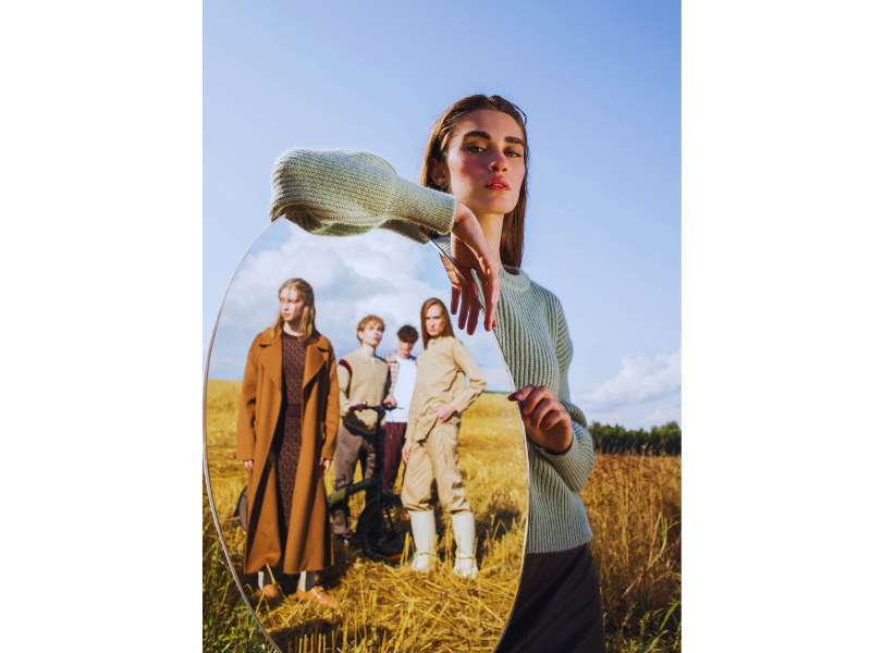 "Woman standing confidently in a field with supportive friends in the background"